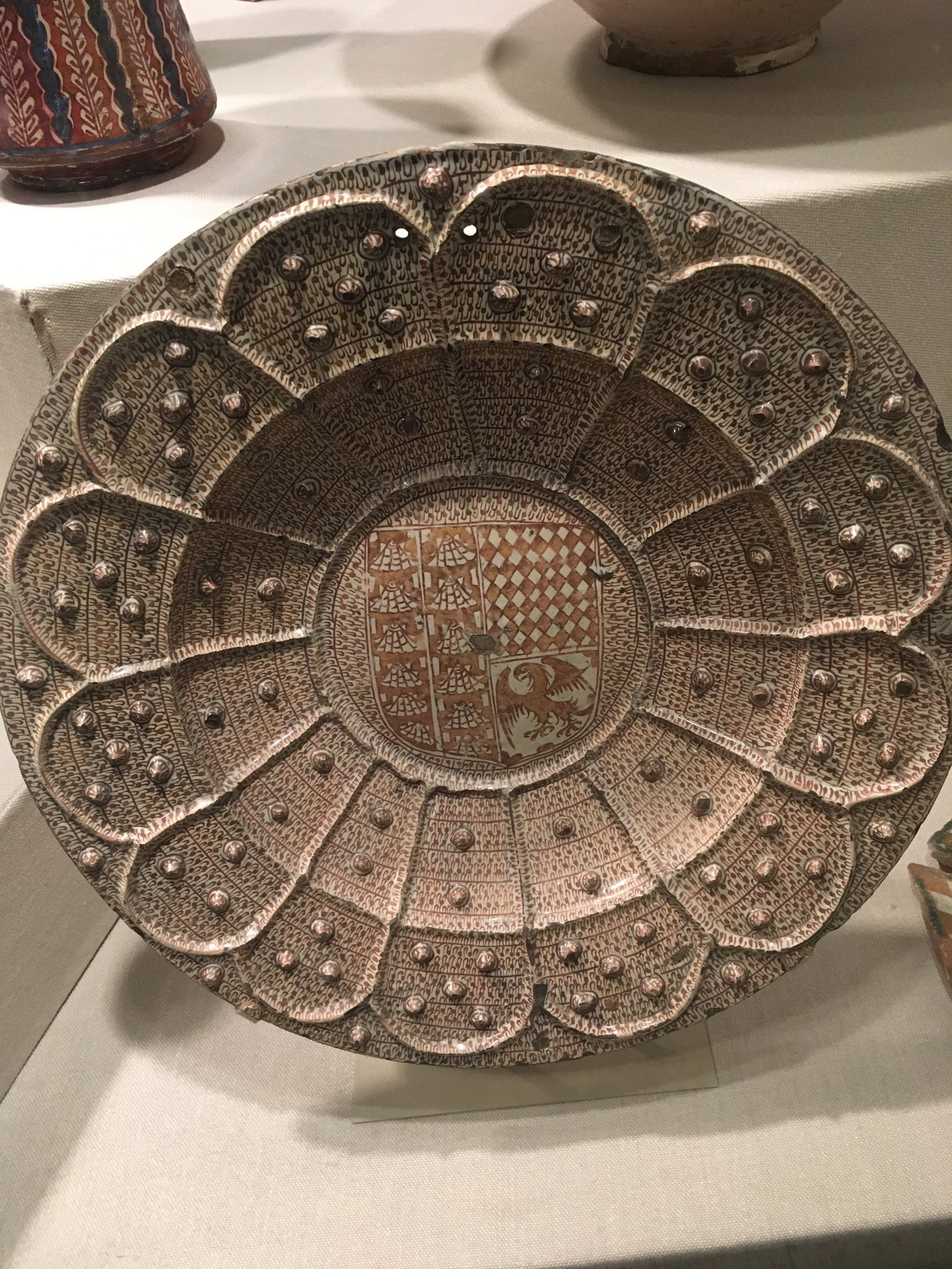 An inlaid plate from Spain with a copper luster and a family shield in the center.