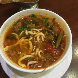 Lagman soup - vegetables noodles and meat in a red broth