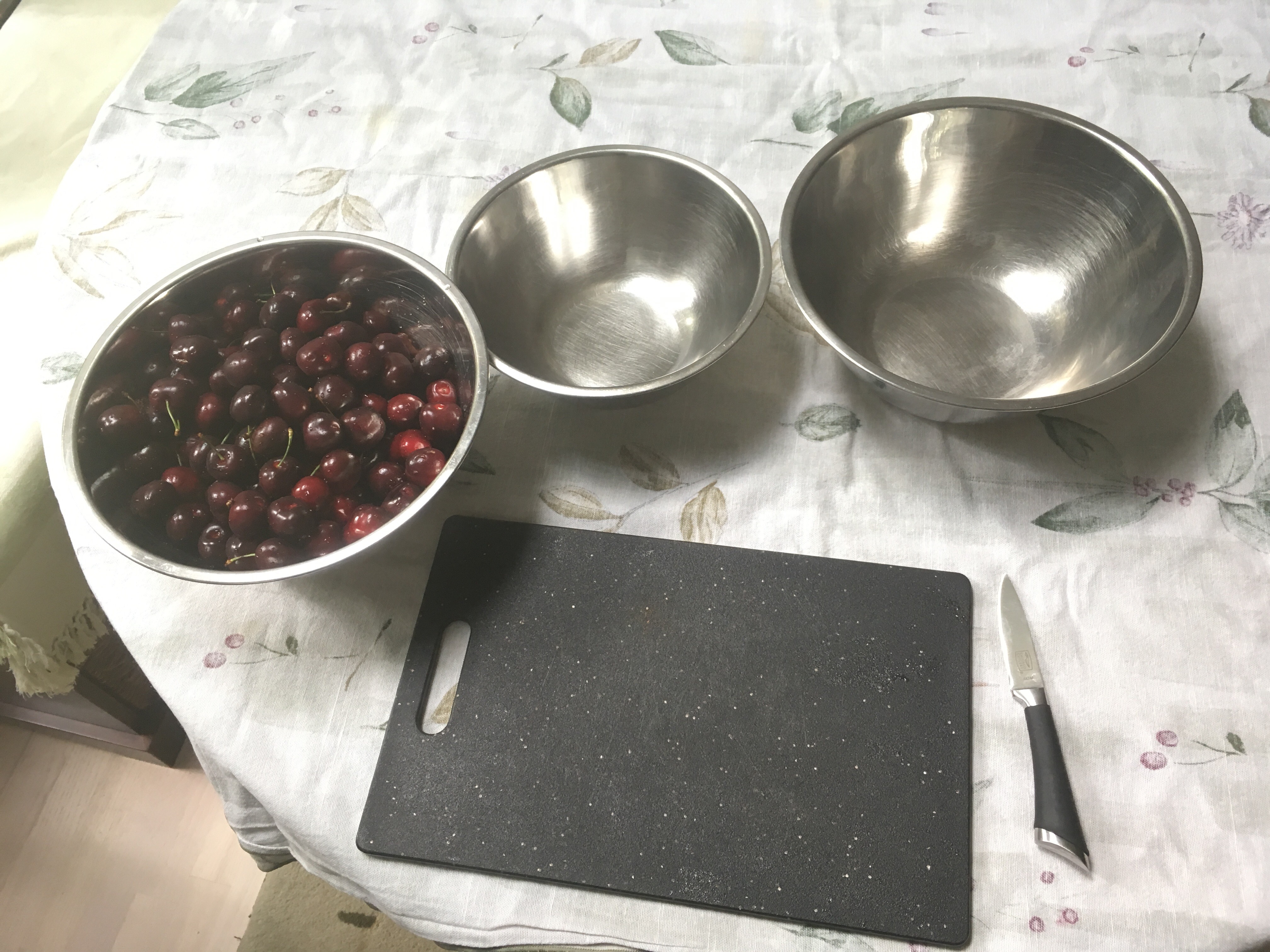 Cherries in a bowl with a knife and board
