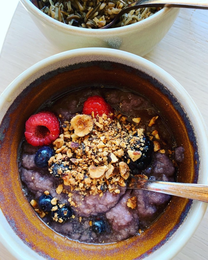 Purple porridge with blueberries, raspberries, and hazelnuts in a bowl